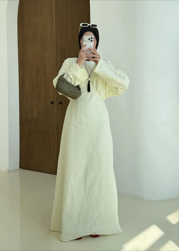 Person wearing a long yellow dress with a plain background