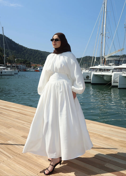 Woman in a white co-ords standing on a dock with boats in the background